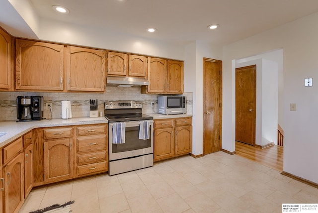 kitchen with stainless steel electric stove, decorative backsplash, and light tile patterned floors