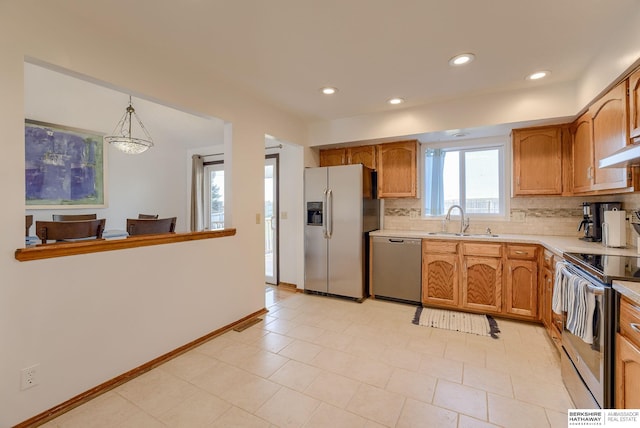 kitchen with pendant lighting, appliances with stainless steel finishes, sink, and tasteful backsplash