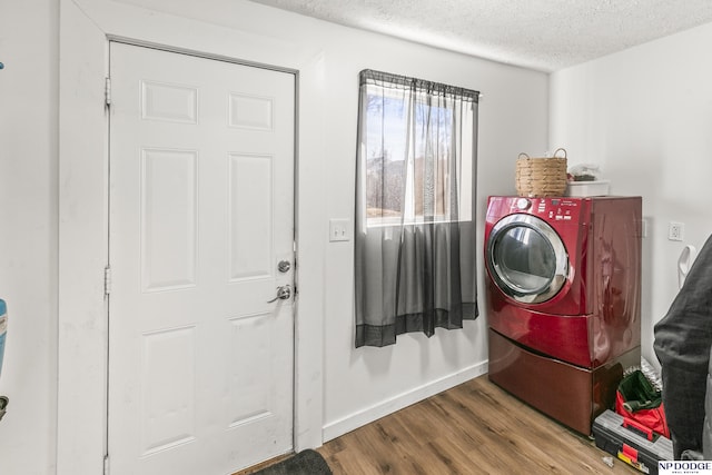 clothes washing area with hardwood / wood-style flooring, washer / clothes dryer, and a textured ceiling