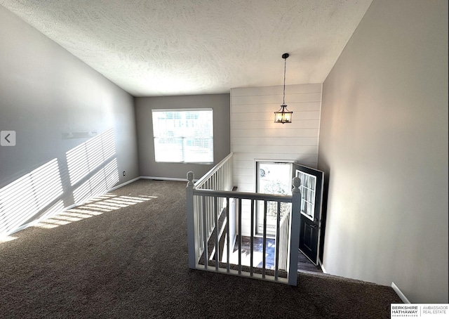 interior space with lofted ceiling, dark carpet, and a textured ceiling