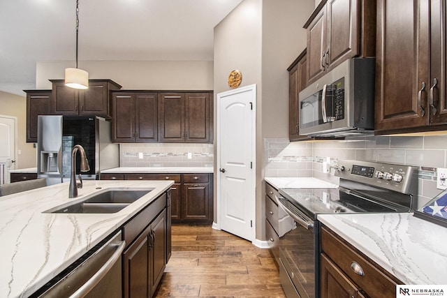 kitchen with pendant lighting, sink, dark brown cabinetry, and appliances with stainless steel finishes