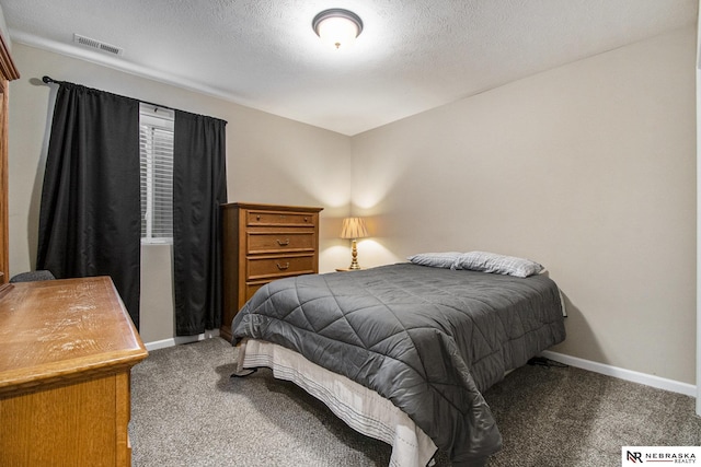 bedroom with a textured ceiling and dark carpet