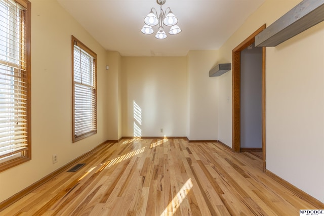 spare room featuring light hardwood / wood-style flooring and a notable chandelier