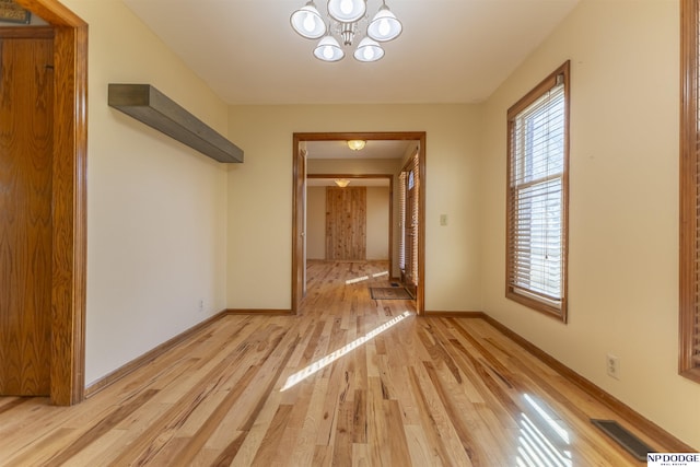 corridor with a notable chandelier and light hardwood / wood-style flooring