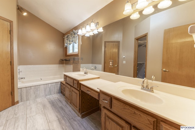 bathroom featuring lofted ceiling, vanity, and tiled tub