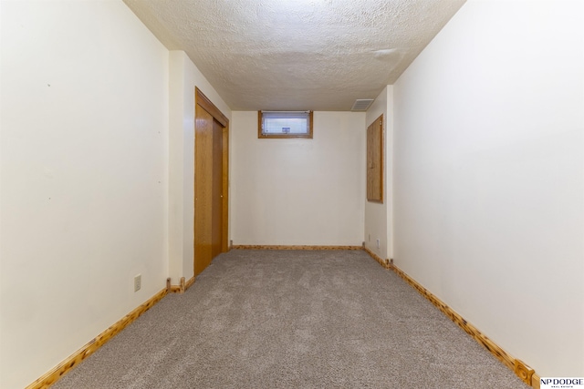 corridor with light colored carpet and a textured ceiling