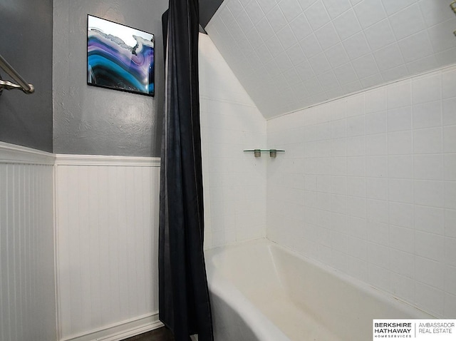 bathroom with shower / tub combo with curtain and lofted ceiling