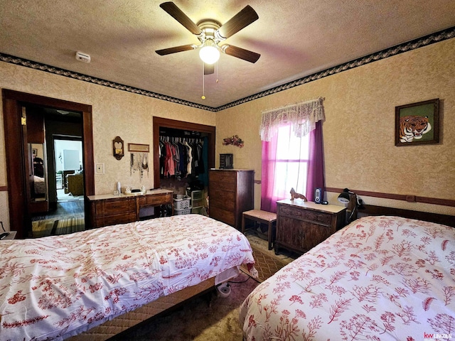 bedroom with a closet, ceiling fan, a textured ceiling, and wallpapered walls