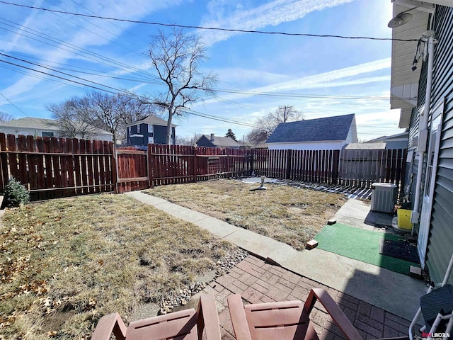 view of yard featuring a fenced backyard, a patio, and central AC unit