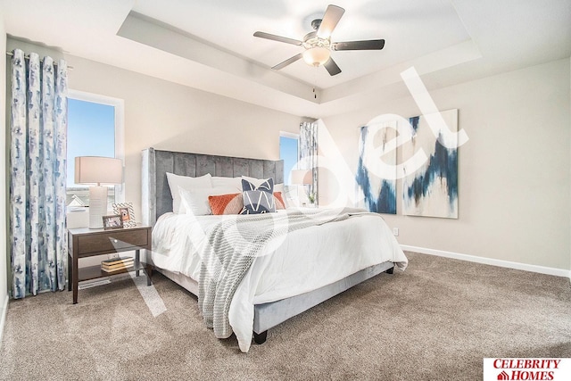 carpeted bedroom featuring a tray ceiling and ceiling fan