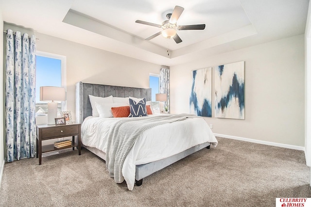 carpeted bedroom featuring a tray ceiling and ceiling fan