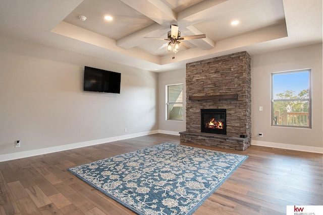 living room with coffered ceiling, a stone fireplace, dark wood-type flooring, and ceiling fan