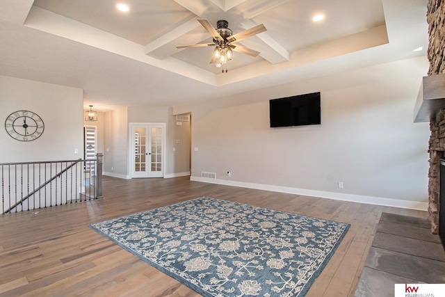 living room with ceiling fan, dark hardwood / wood-style floors, coffered ceiling, a fireplace, and a raised ceiling