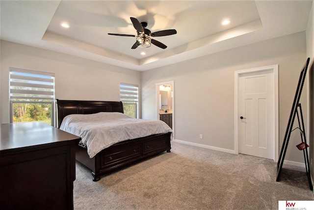 carpeted bedroom featuring a raised ceiling, ceiling fan, and ensuite bathroom