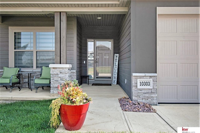 view of exterior entry featuring a garage and covered porch