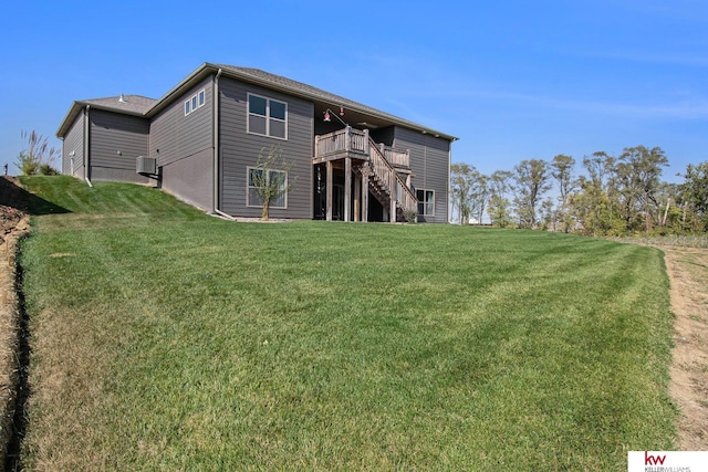 rear view of house featuring a wooden deck and a yard