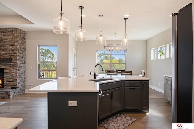 kitchen with sink, dark hardwood / wood-style floors, hanging light fixtures, and a center island with sink