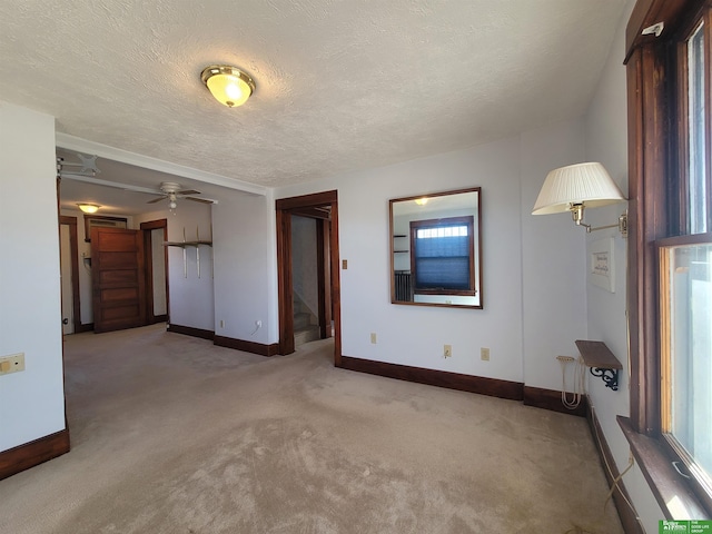 unfurnished living room with ceiling fan, light colored carpet, and a textured ceiling