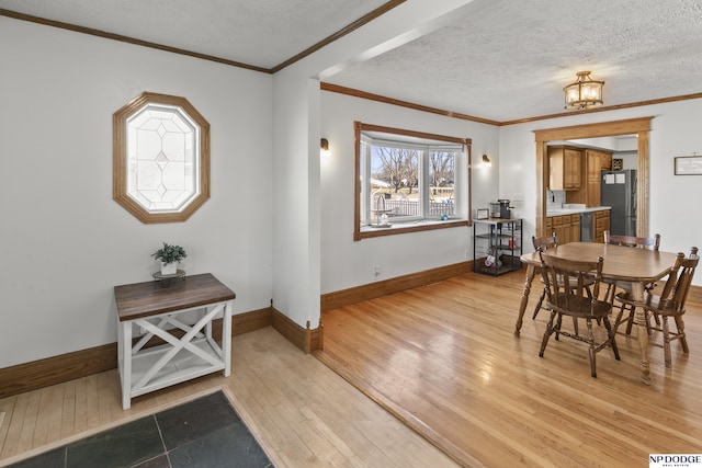 dining room featuring ornamental molding, sink, a textured ceiling, and light hardwood / wood-style floors