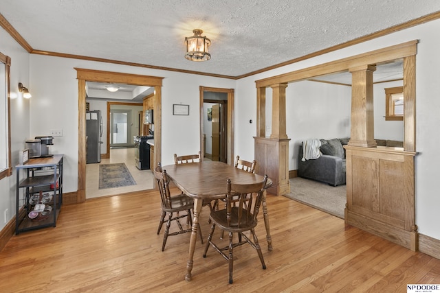 dining area with decorative columns, crown molding, a textured ceiling, and light hardwood / wood-style floors