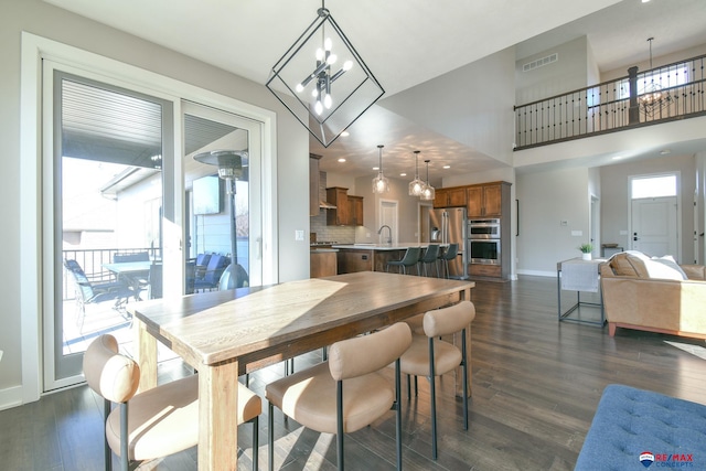 dining space with dark hardwood / wood-style flooring, a notable chandelier, and a towering ceiling