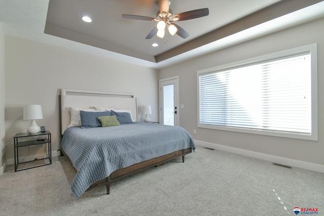 carpeted bedroom featuring ceiling fan and a raised ceiling