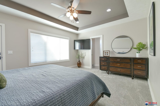 carpeted bedroom with ceiling fan and a tray ceiling