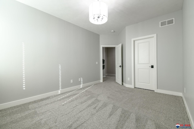 unfurnished bedroom featuring an inviting chandelier and carpet