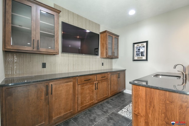 kitchen with dark tile patterned flooring, sink, and dark stone countertops