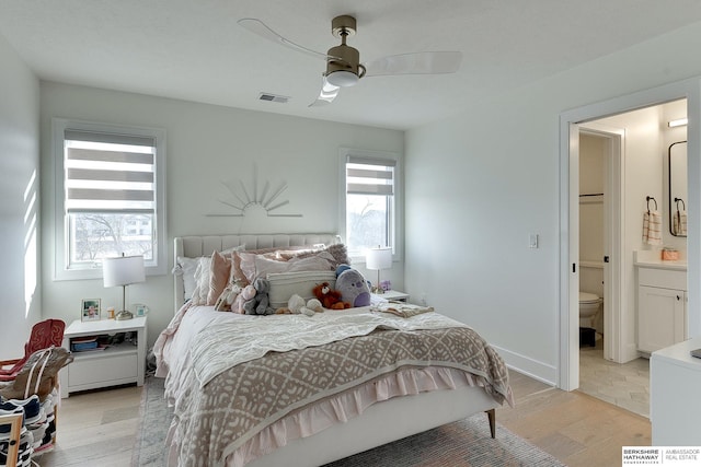 bedroom with ceiling fan, light wood-type flooring, and ensuite bath