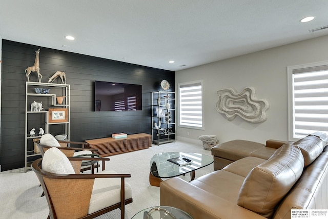 carpeted living room featuring wood walls