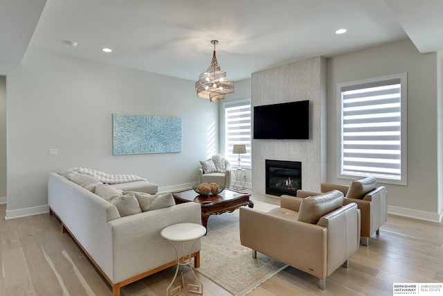 living room featuring a large fireplace, a chandelier, and light wood-type flooring