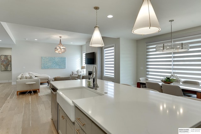 kitchen featuring sink, decorative light fixtures, light hardwood / wood-style flooring, and a wealth of natural light