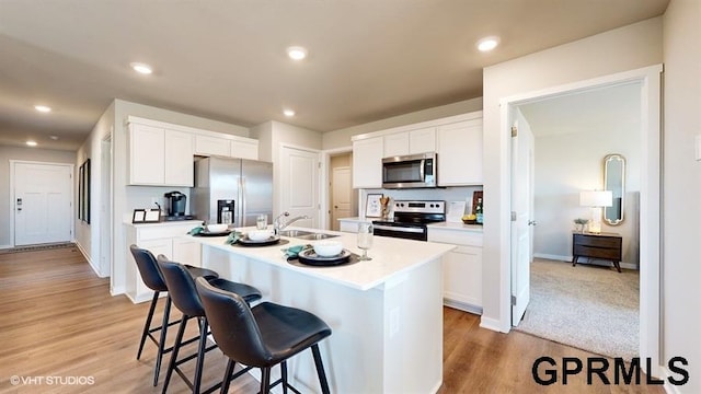 kitchen featuring white cabinetry, stainless steel appliances, sink, and an island with sink