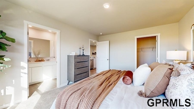 bedroom with ensuite bathroom, a spacious closet, light carpet, and a closet