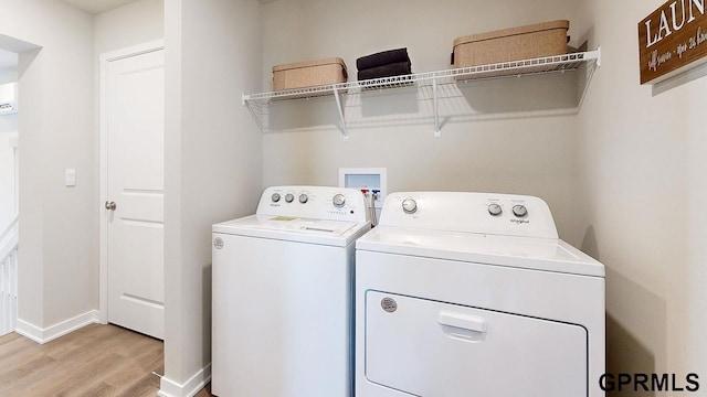 laundry area with washer and clothes dryer and light wood-type flooring