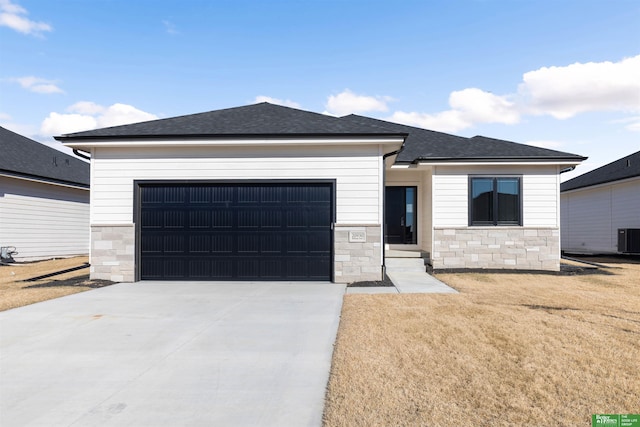 view of front of home featuring a garage, a front lawn, and central air condition unit