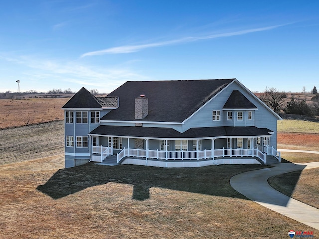 view of front of house with a porch, a front yard, driveway, and a chimney