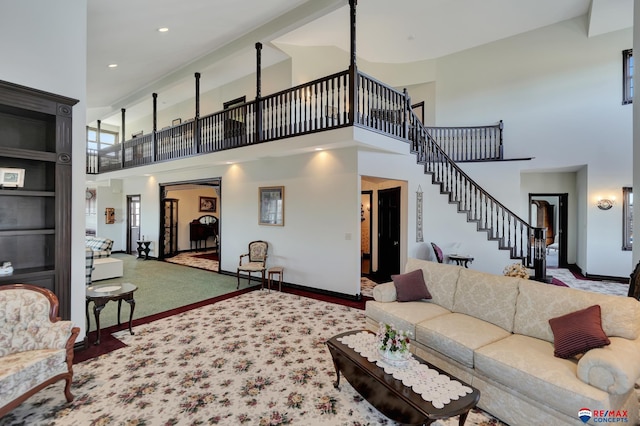 living area featuring a towering ceiling, recessed lighting, stairway, and baseboards