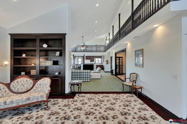 sitting room featuring carpet flooring, a towering ceiling, and baseboards