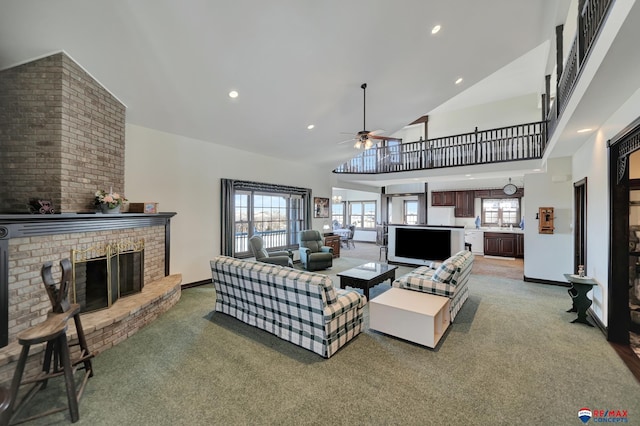 living room featuring baseboards, a ceiling fan, carpet floors, a fireplace, and high vaulted ceiling