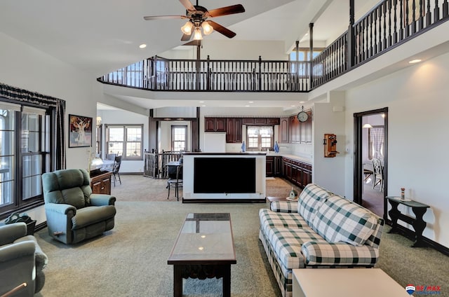 living area featuring light carpet, a towering ceiling, and a wealth of natural light