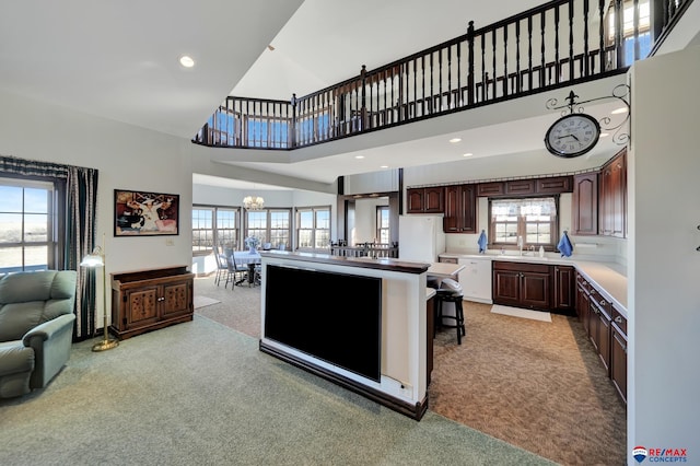 kitchen with light colored carpet, light countertops, a high ceiling, open floor plan, and white appliances