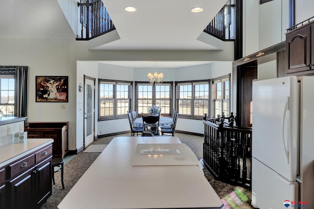 kitchen featuring light countertops, hanging light fixtures, freestanding refrigerator, and dark brown cabinetry