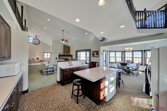 kitchen featuring a center island, light colored carpet, light countertops, open floor plan, and white appliances