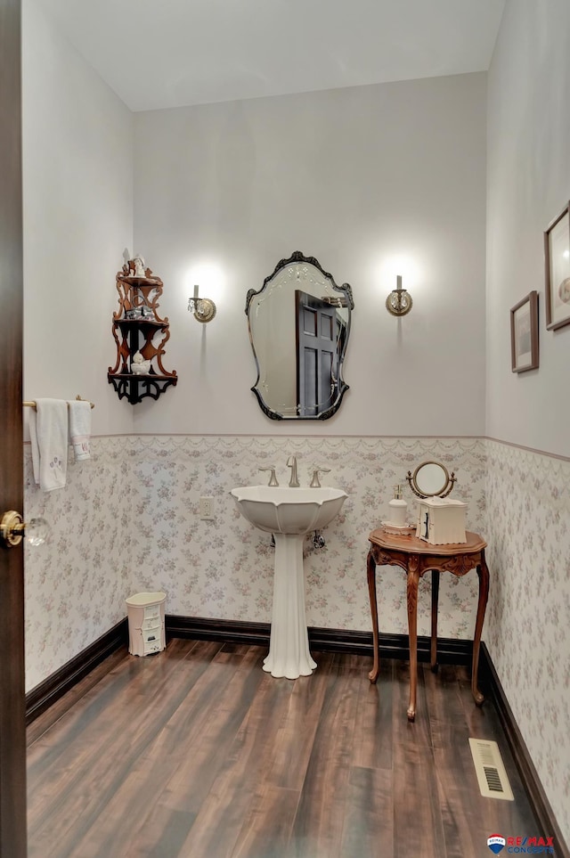 bathroom featuring wood finished floors, visible vents, baseboards, and wallpapered walls