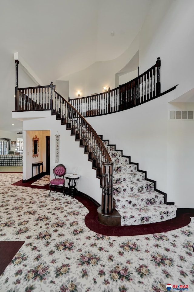 stairs featuring carpet floors, a towering ceiling, and visible vents