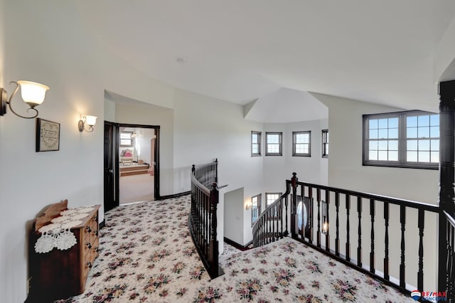 hall with lofted ceiling, baseboards, an upstairs landing, and light colored carpet