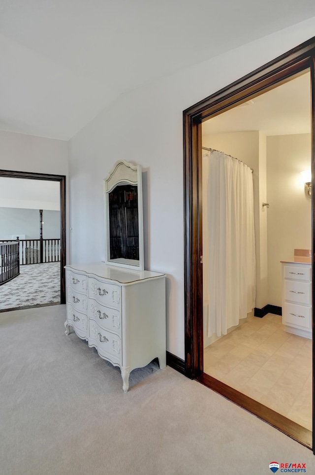 interior space featuring light carpet, baseboards, and vaulted ceiling