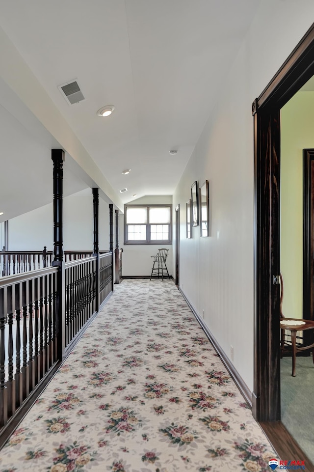 hall featuring visible vents, vaulted ceiling, and carpet flooring